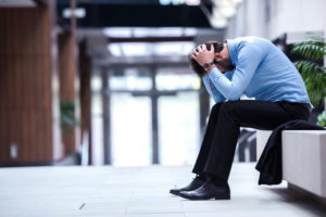man seated blue shirt head in hands more job interview mistakes